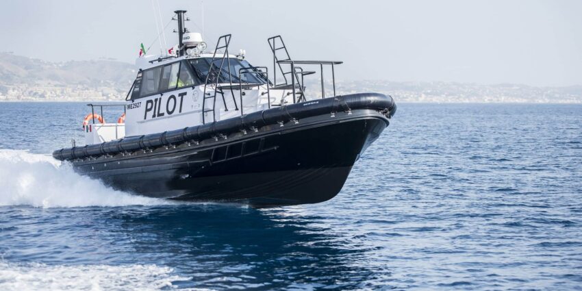 A white and black pilot boat glides across an open body of water.